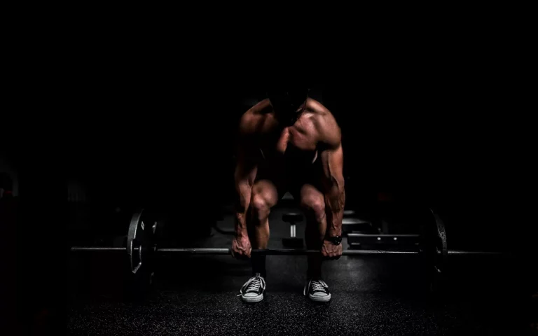topless man in black shorts sitting on black and silver barbell