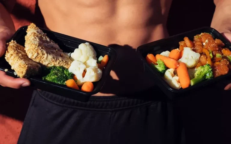 topless man in black shorts holding cooked food at DietPal nutrition and using Herbalife to lose weight